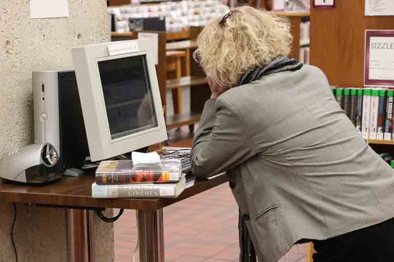 a lady looking through the relational database of a library