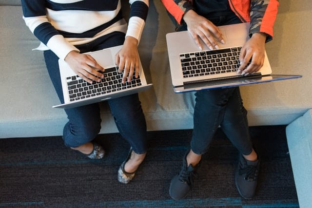 Two people holding Macbook pro